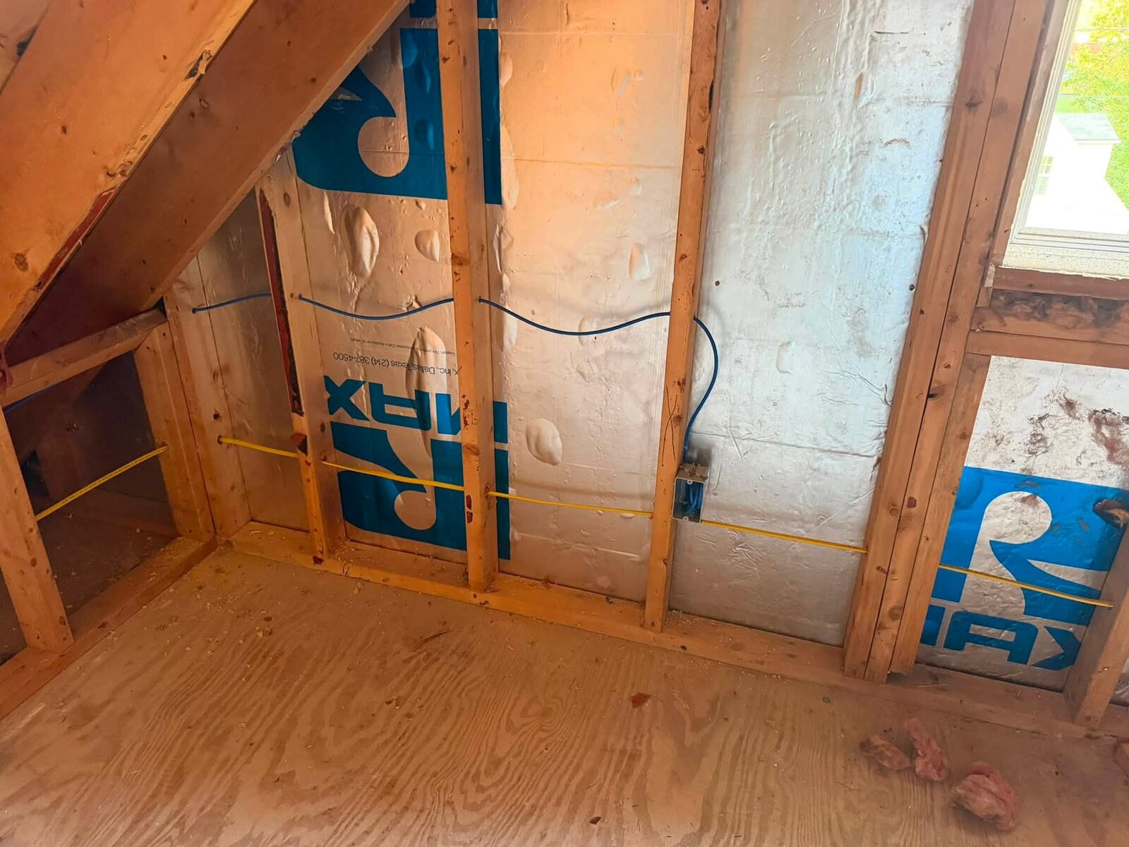 Bundled low-voltage cable runs through floor joists during a rough-in