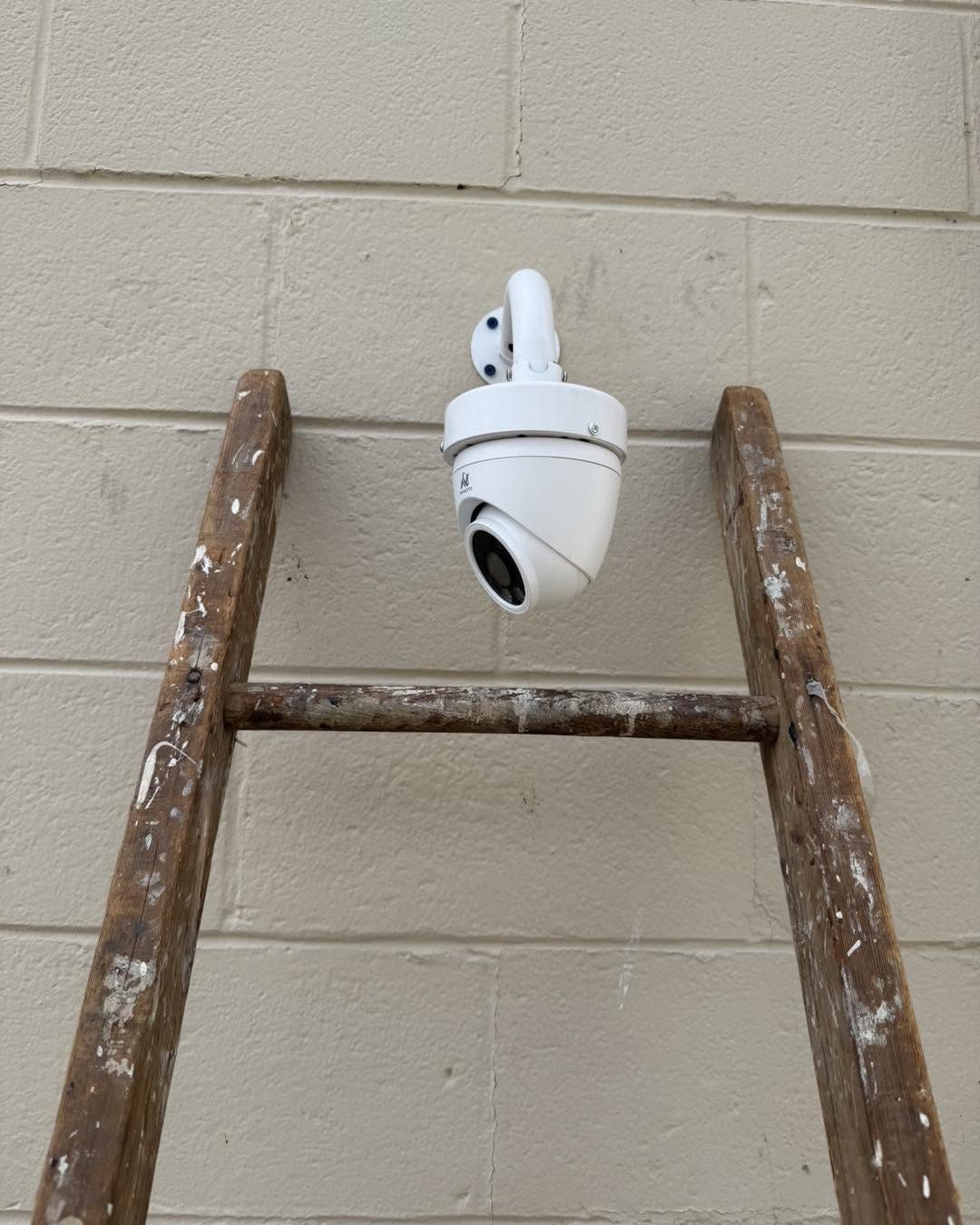 White dome security camera mounted on the exterior block wall of a commercial building