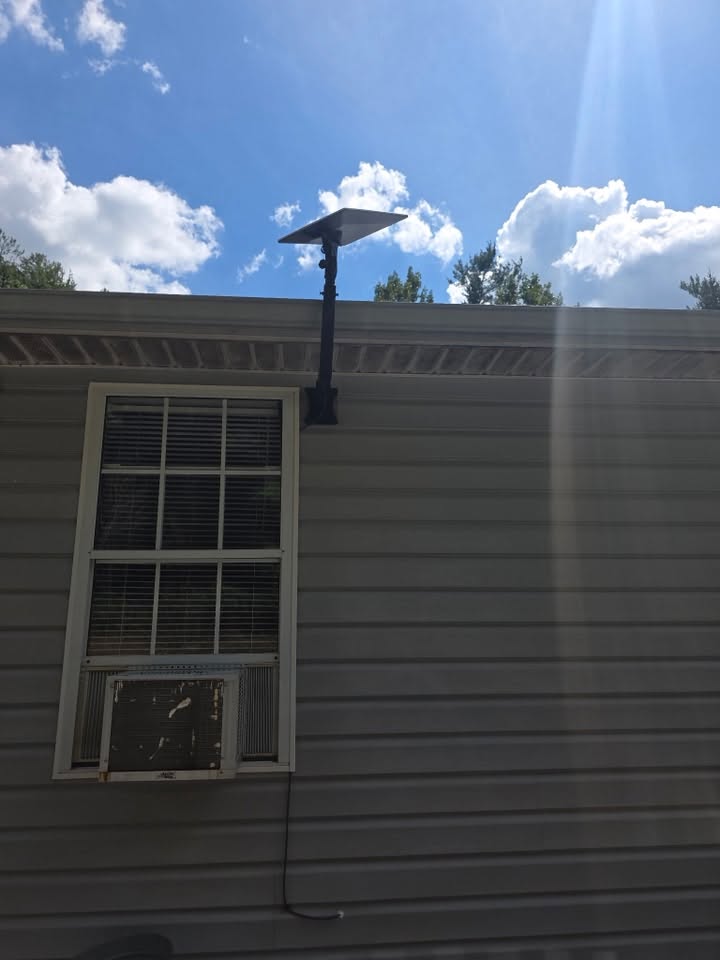 Starlink dish on a pole mount above a home roofline
